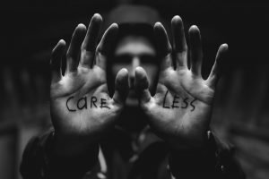 gray scale photography of man raising both hands with care less text on palm