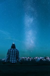 man sitting on gray wall looking at the stars