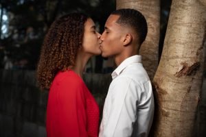 man in white dress shirt kissing woman in red dress