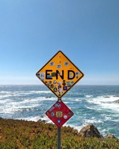 yellow and black road sign near sea during daytime