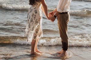 woman holding hands in front of man standing on seashore